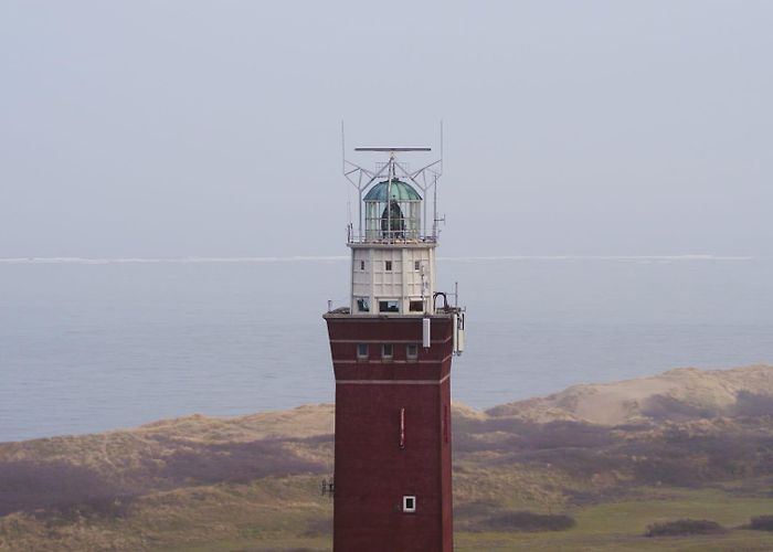 Westhoofd Lighthouse Circling A Red Lighthouse In Front Of Fields, The Ocean - Ungraded photo